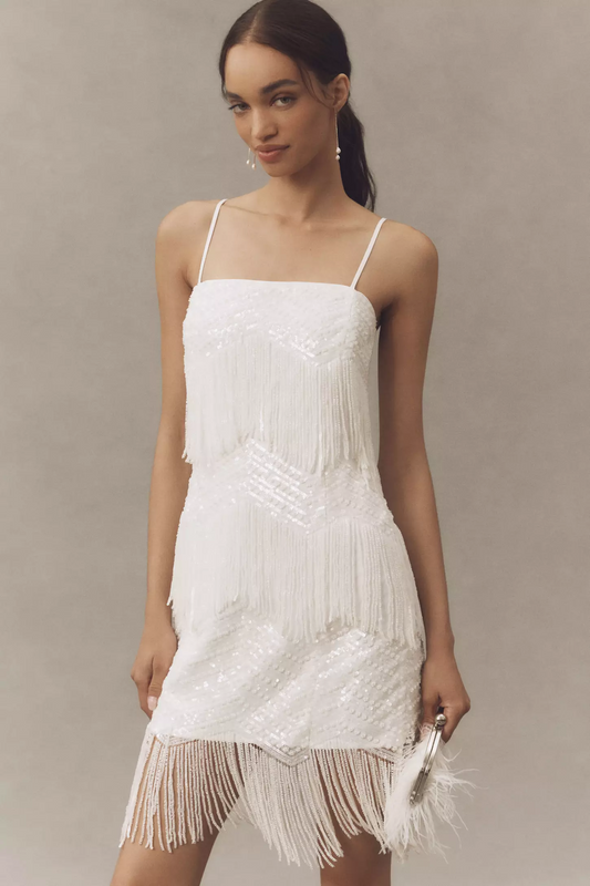 White fringe dress worn by a model against a neutral background